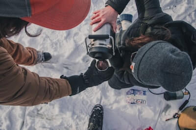 雪山で飲み物を飲んでいる人
